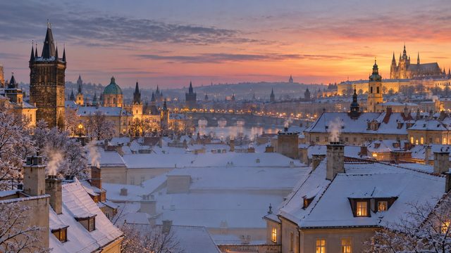 Snow-covered rooftops in an old city at dusk with chimney smoke - free Christmas background